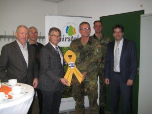 Stolz präsentiert Bürgermeister Gottlieb imBeisein von Kommunalpolikern und der Vertreter der DSK die "Gelbe Schleife" für Birstein.